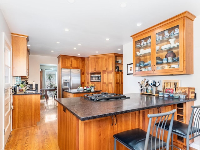 kitchen with dark countertops, black appliances, a peninsula, and light wood-style floors