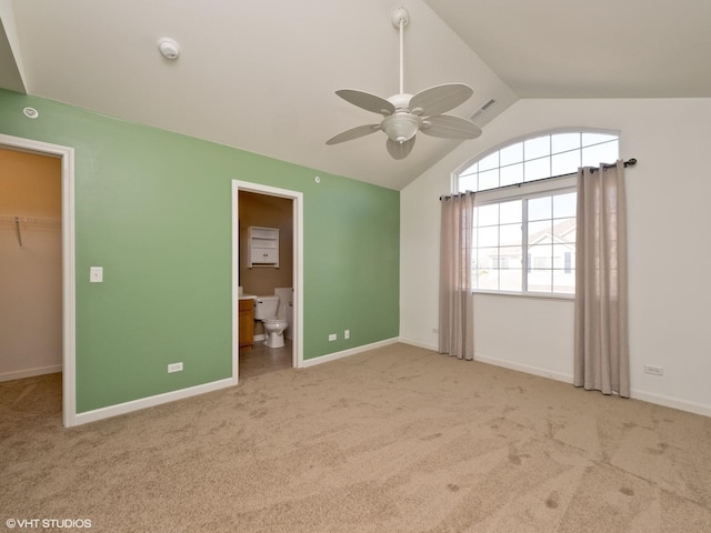 unfurnished bedroom featuring baseboards, lofted ceiling, a spacious closet, a closet, and carpet flooring