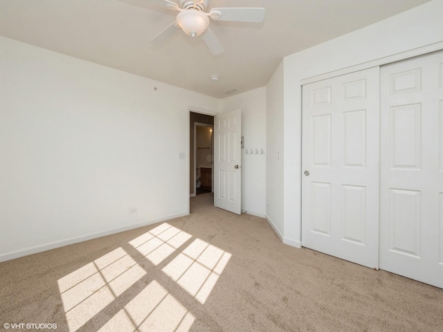 unfurnished bedroom featuring a ceiling fan, visible vents, baseboards, a closet, and light carpet