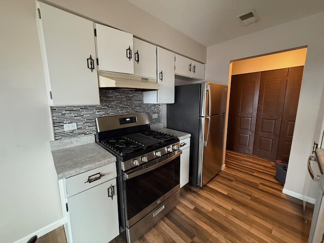 kitchen featuring visible vents, appliances with stainless steel finishes, dark wood-type flooring, light countertops, and under cabinet range hood