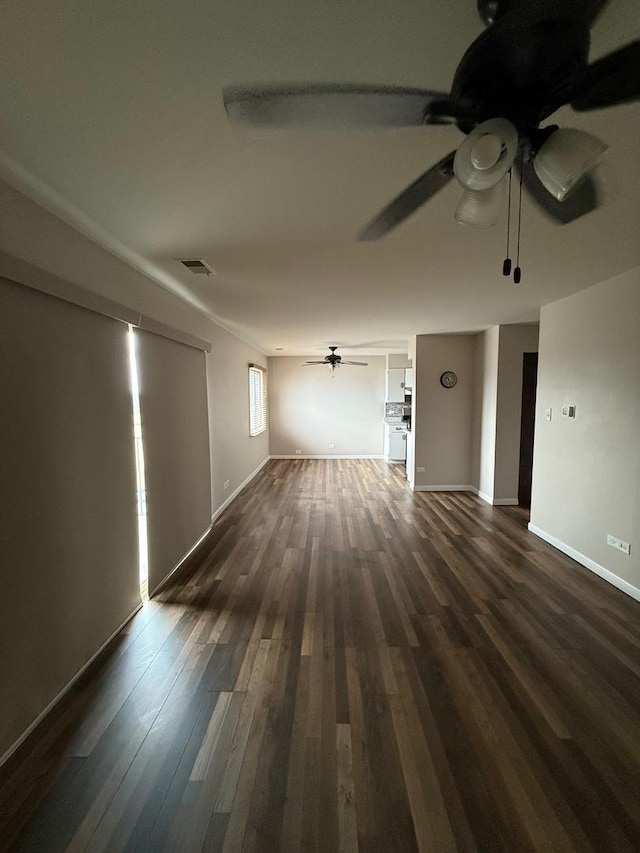 spare room featuring dark wood-type flooring, visible vents, baseboards, and a ceiling fan