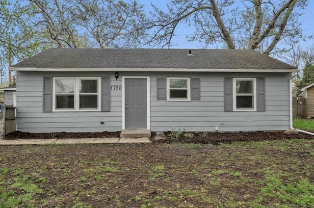 view of front of property with roof with shingles and fence