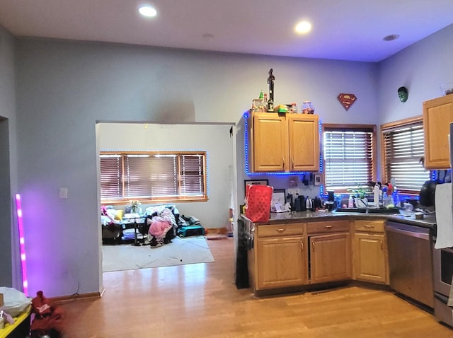 kitchen with dishwasher, dark countertops, light wood-style flooring, and a sink