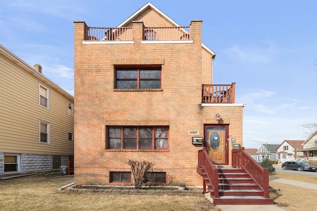 view of front of property with brick siding and a balcony