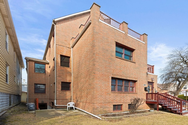 rear view of property featuring brick siding and a balcony