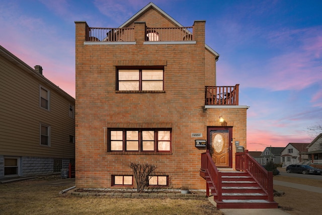 view of front facade featuring a balcony and brick siding