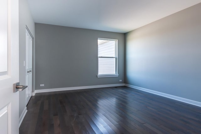 spare room featuring dark wood-style floors and baseboards