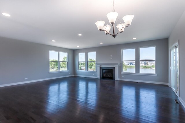 unfurnished living room with a chandelier, dark wood finished floors, and baseboards