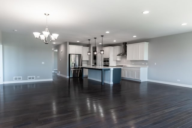 kitchen featuring stainless steel appliances, open floor plan, visible vents, and wall chimney exhaust hood