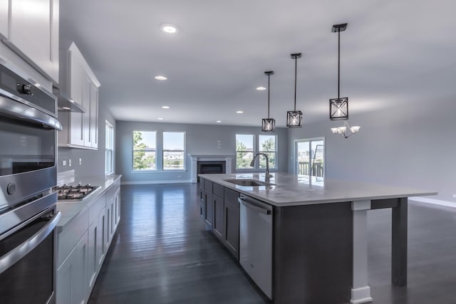 kitchen with dark wood-style floors, open floor plan, stainless steel appliances, white cabinetry, and a sink