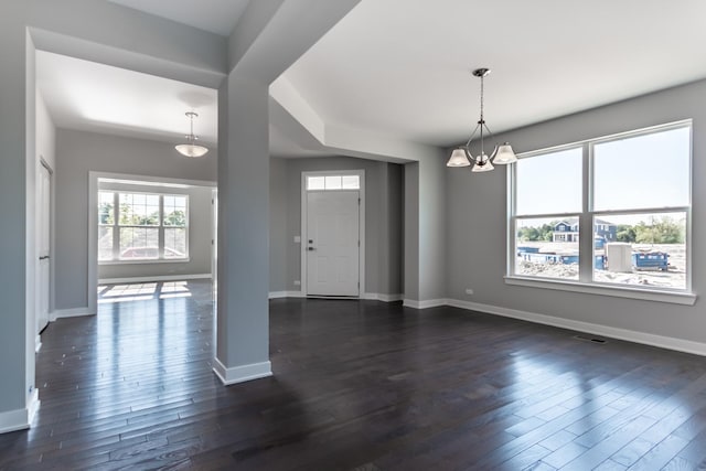 foyer featuring baseboards, dark wood finished floors, visible vents, and a notable chandelier