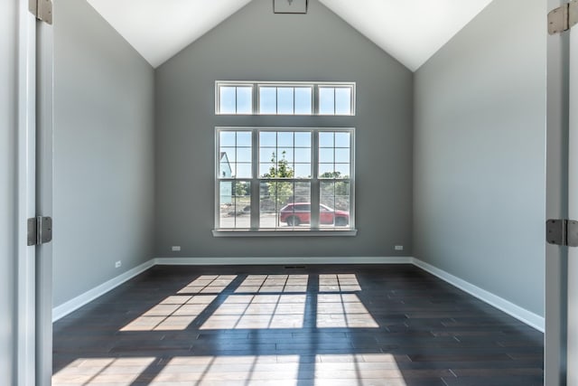 empty room featuring lofted ceiling, baseboards, and wood finished floors