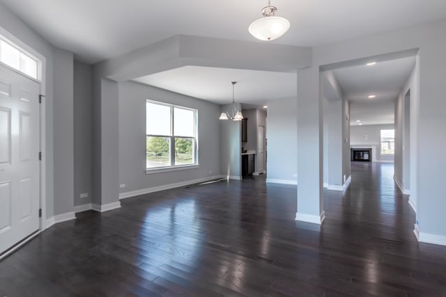 entrance foyer with baseboards, dark wood-type flooring, and a glass covered fireplace