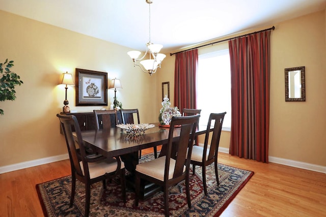 dining space featuring a notable chandelier, baseboards, and wood finished floors