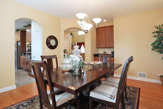 dining space featuring baseboards, a notable chandelier, visible vents, and light wood-style floors