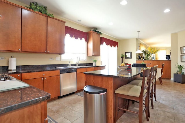 kitchen featuring light tile patterned floors, a breakfast bar area, a sink, a center island, and dishwasher