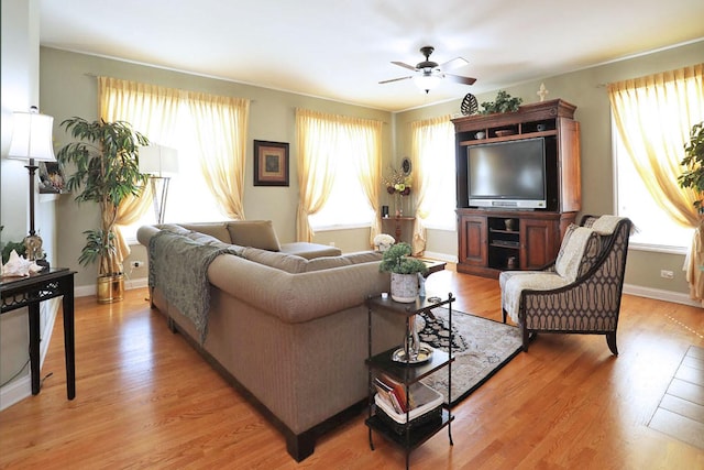 living room with baseboards, a ceiling fan, and light wood-style floors