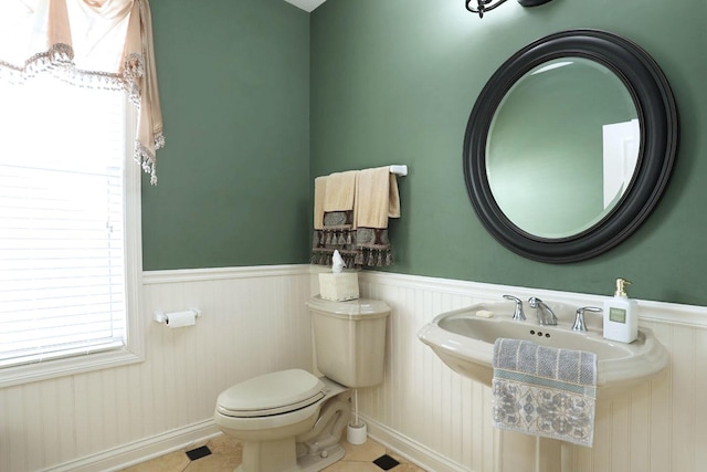 bathroom featuring a wainscoted wall, tile patterned flooring, and toilet