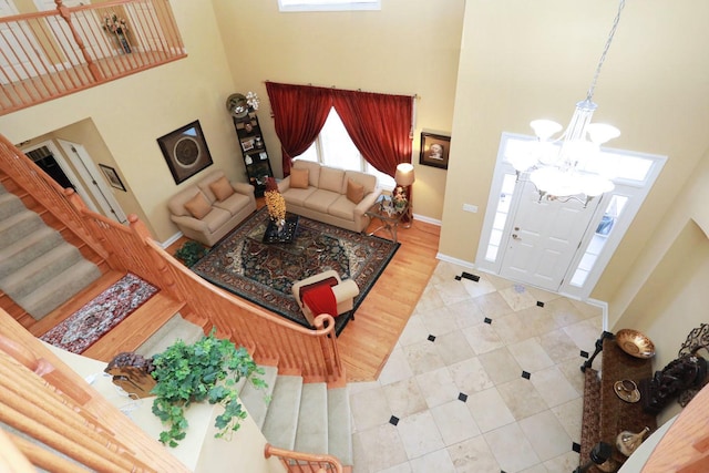 living area with stairs, a high ceiling, a chandelier, and baseboards