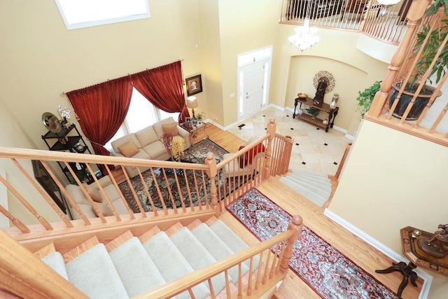 stairway with a chandelier, a high ceiling, wood finished floors, and baseboards