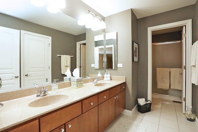 bathroom with double vanity, tile patterned flooring, baseboards, and a sink