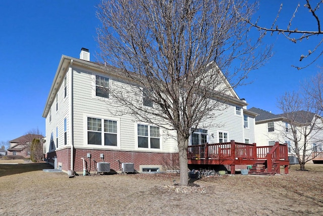 back of house featuring central air condition unit, a chimney, a deck, and brick siding