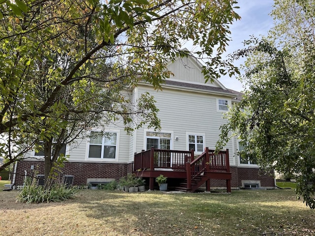 rear view of house featuring brick siding, a yard, and a deck