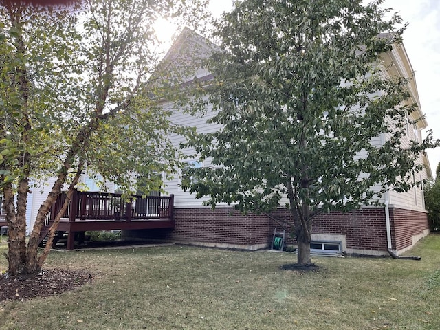 exterior space with brick siding, a lawn, and a deck