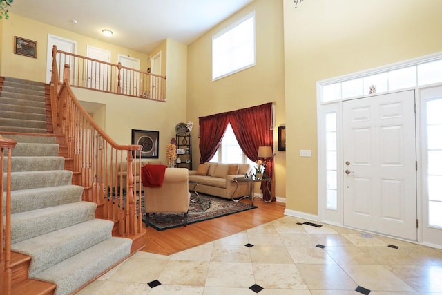 tiled foyer featuring a towering ceiling, stairway, and baseboards