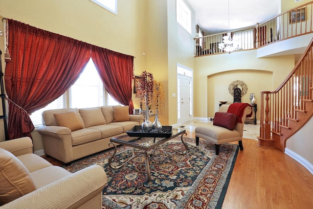 living area featuring stairs, baseboards, wood finished floors, and a chandelier