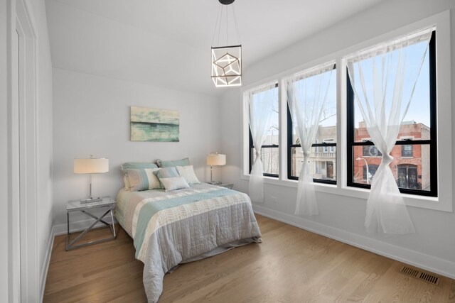 bedroom featuring visible vents, baseboards, and wood finished floors