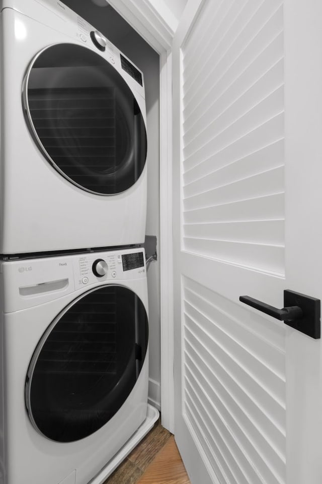 laundry room with stacked washer and dryer, wood finished floors, and laundry area