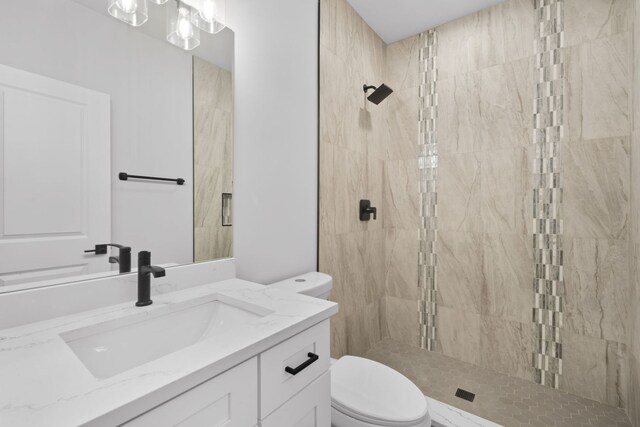 bathroom with toilet, tiled shower, and vanity