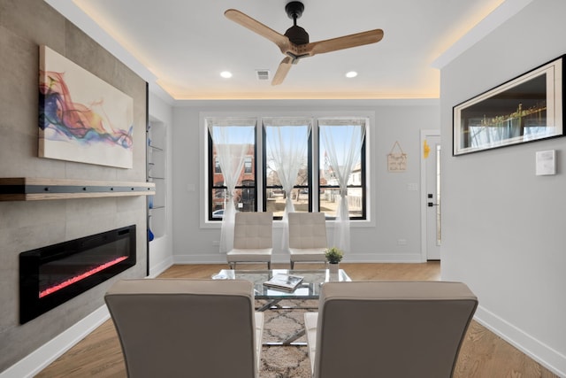 living room featuring baseboards, visible vents, wood finished floors, built in shelves, and a fireplace