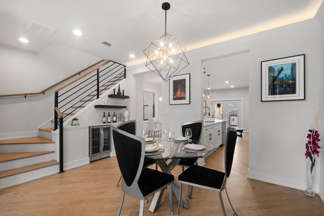 dining area with beverage cooler, light wood finished floors, stairway, and visible vents