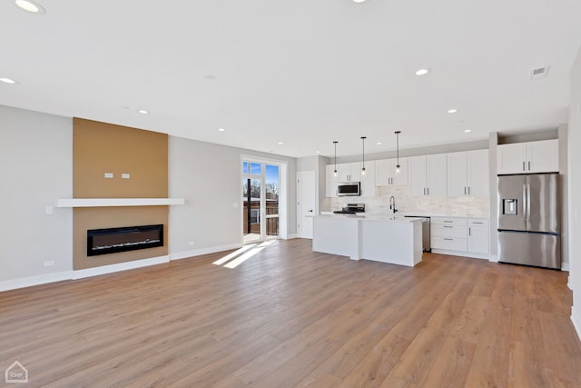 kitchen featuring stainless steel appliances, tasteful backsplash, light countertops, light wood-style flooring, and white cabinets