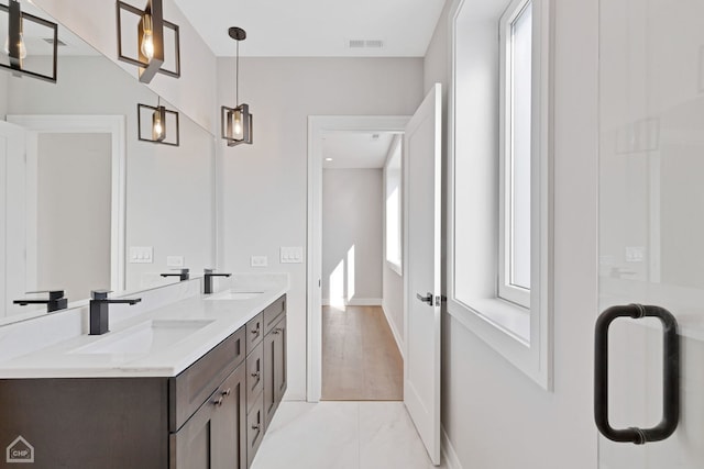 bathroom with visible vents, a sink, baseboards, and double vanity