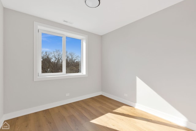 empty room featuring visible vents, baseboards, and wood finished floors