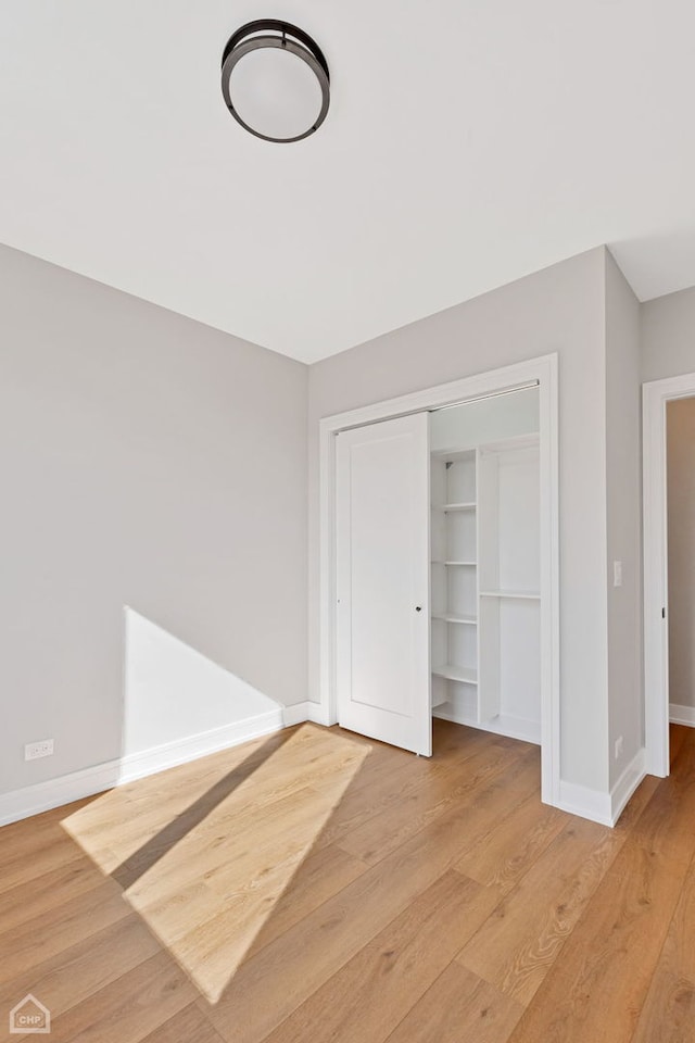 unfurnished bedroom with a closet, light wood-style flooring, and baseboards