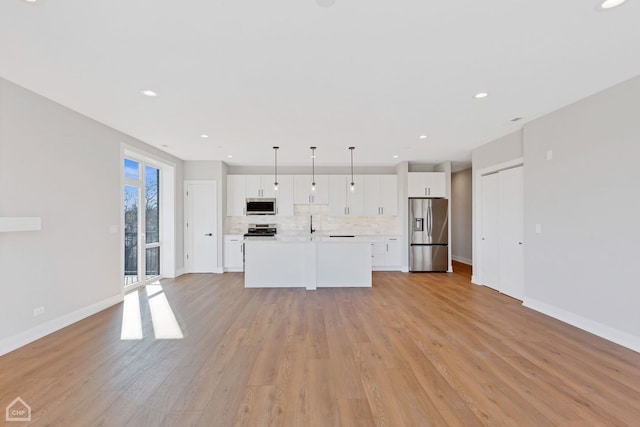 kitchen with light wood finished floors, tasteful backsplash, appliances with stainless steel finishes, light countertops, and white cabinetry