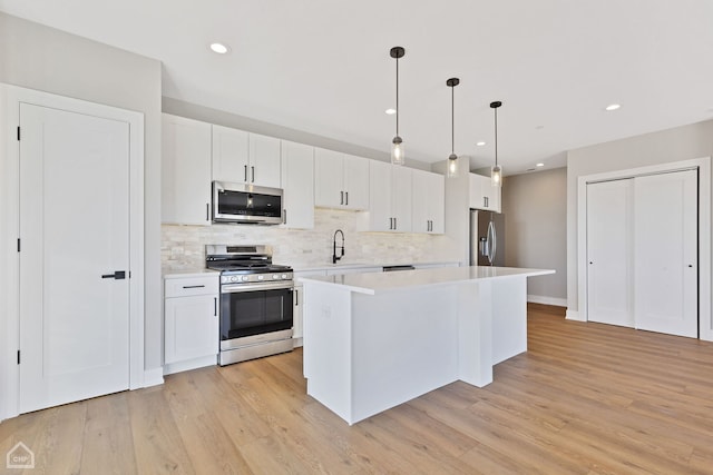 kitchen with light wood finished floors, stainless steel appliances, a sink, and light countertops