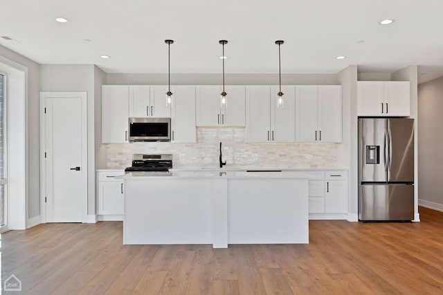 kitchen featuring stainless steel appliances, light countertops, white cabinets, and a center island