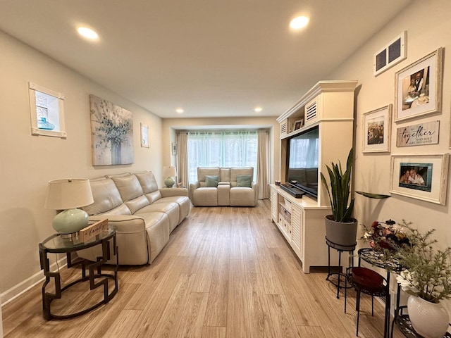 living room featuring recessed lighting, visible vents, baseboards, light wood-style floors, and a glass covered fireplace