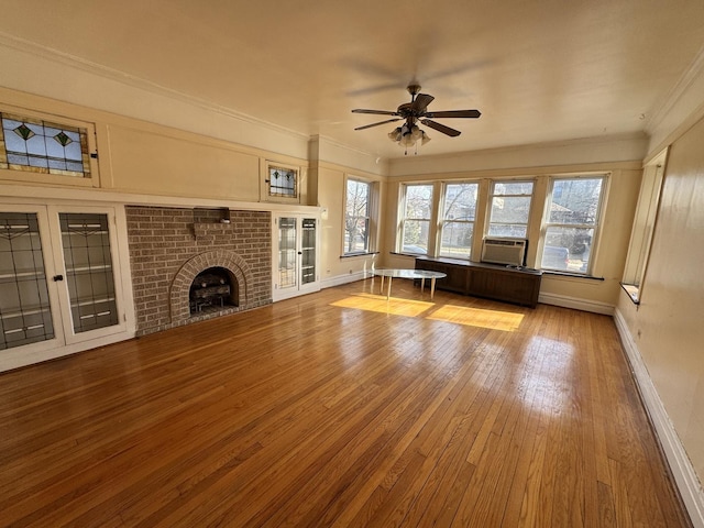 unfurnished living room with a healthy amount of sunlight, a brick fireplace, hardwood / wood-style flooring, and crown molding