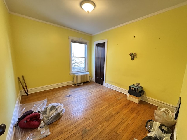 unfurnished room featuring radiator, crown molding, wood-type flooring, and baseboards