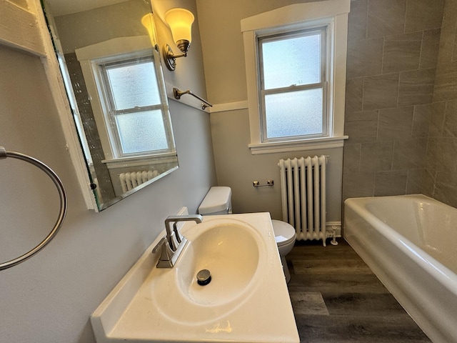 full bathroom with radiator, toilet, a sink, and wood finished floors