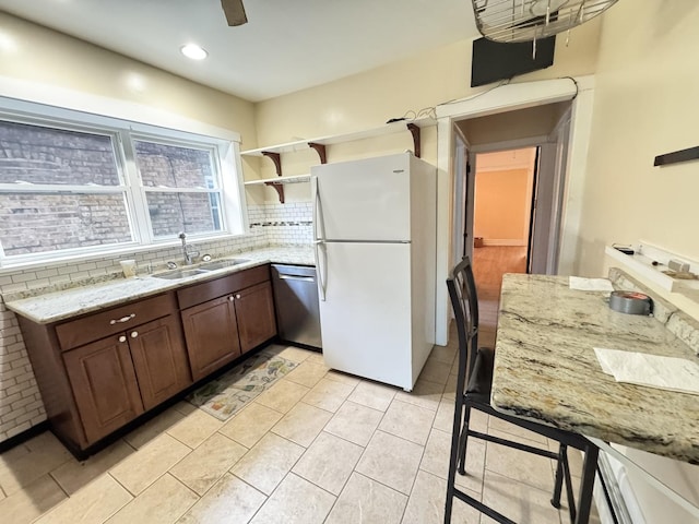 kitchen with open shelves, tasteful backsplash, stainless steel dishwasher, freestanding refrigerator, and a sink