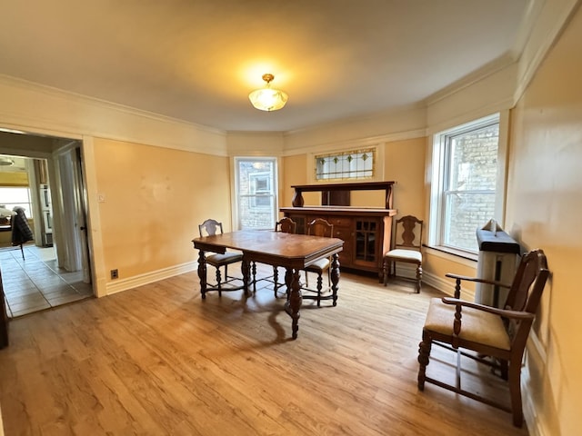 dining room featuring light wood-style flooring, ornamental molding, and baseboards