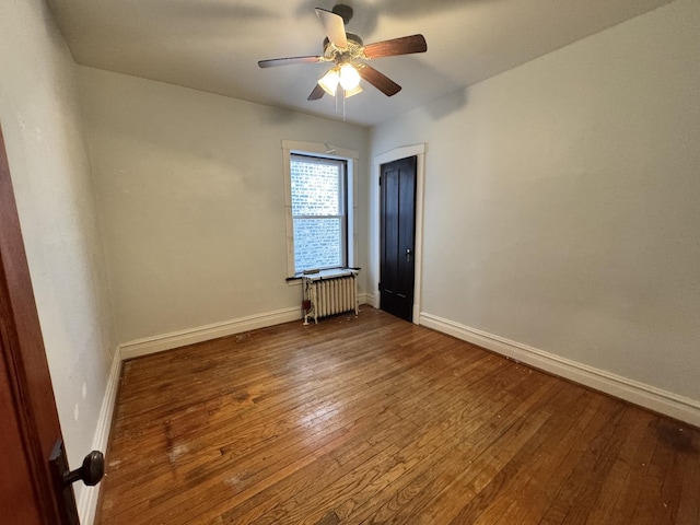 unfurnished room with radiator, ceiling fan, baseboards, and hardwood / wood-style flooring