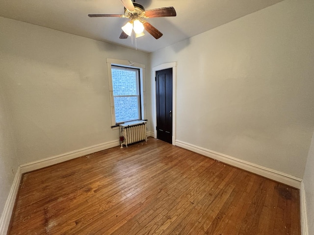 spare room featuring radiator, hardwood / wood-style flooring, and baseboards